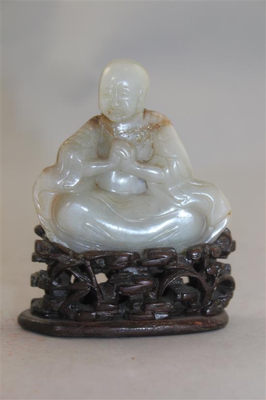 A Chinese white and russet jade carving of a luohan, 18th / 19th century, 6.7cm, neck broken and restuck, intricately carved rosewood s